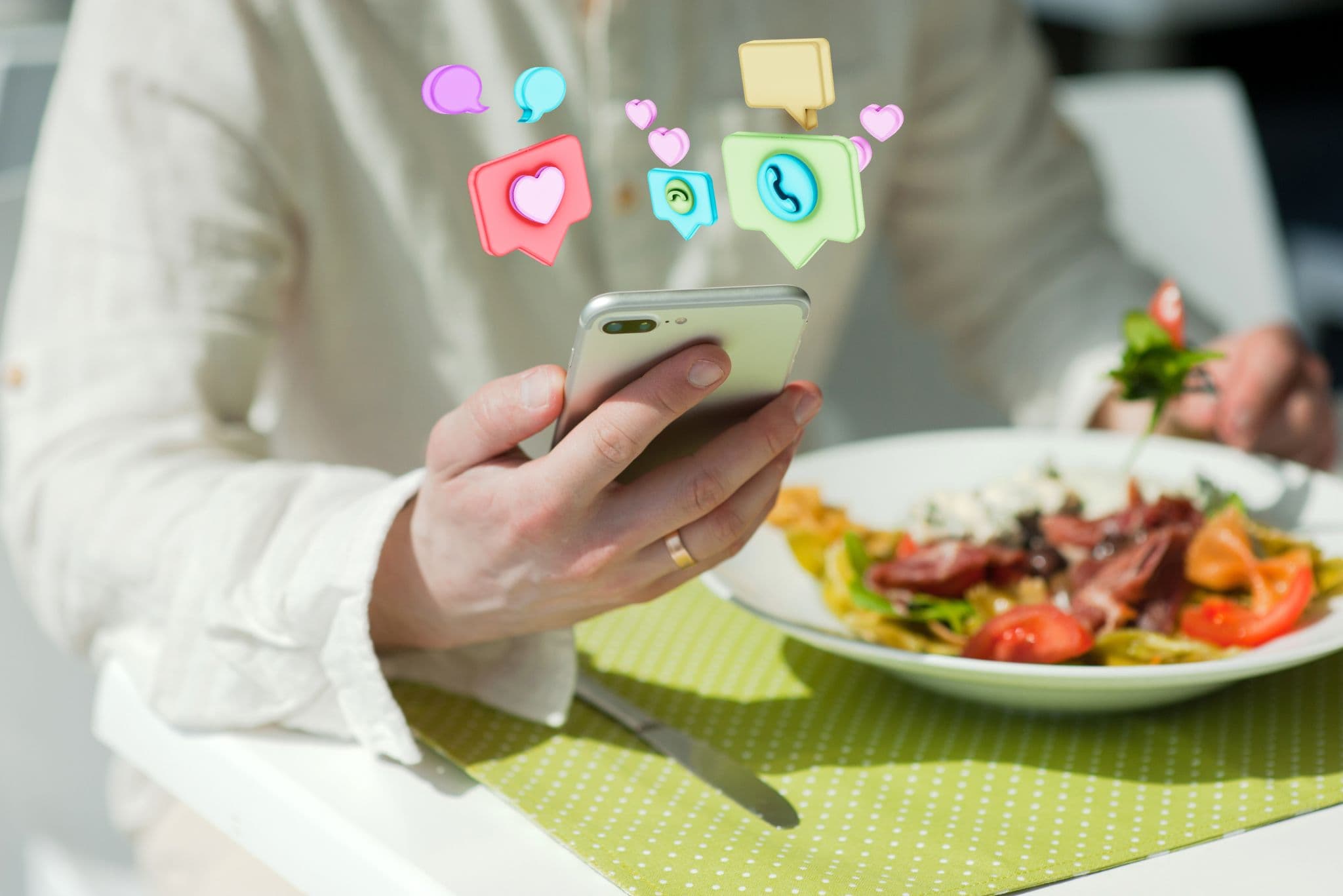 Imágen de una persona con su teléfono usando las redes sociales mientras tiene un plato de comida al lado
